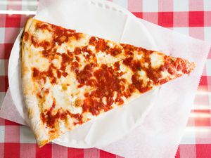 A slice of New York pizza (from Sac's Place) on a paper plate.