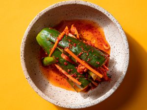 Overhead of a piece of stuffed cucumber kimchi in a small serving bowl.