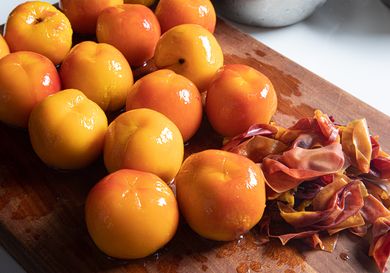 Peeled peaches on a cutting board.