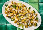 Bright colorful photo of grilled corn, topped with sauce, cheese cilantro and limes.