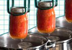 Canned tomatoes being lifted from a pot