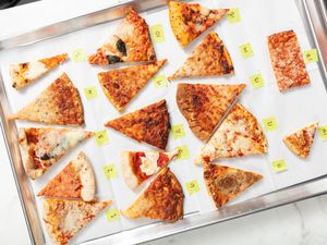 Several different types of frozen pizza on a parchment paper lined sheet pan with numbers next to them