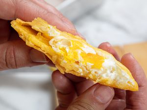 Side view of hands holding arepa de huevo