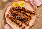 Honey harissa glazed chicken skewers on a platter with lemon slices