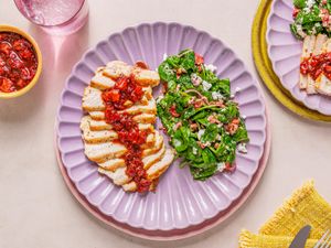 A plate of sliced pork chops with strawberry balsamic glaze and a side of spinach salad