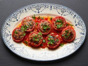 A platter of Vietnamese-style pork-stuffed tomatoes garnished with herbs