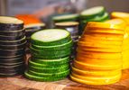 Stacked slices of green zucchini and yellow squash on a cutting board, arranged neatly