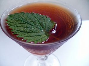 A cocktail glass with a cocktail garnished with a shiso leaf.