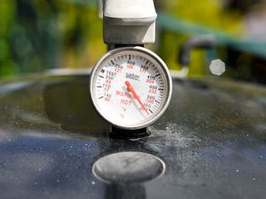 A thermometer on top of a grill.