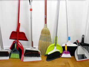 a variety of kitchen brooms leaning against a wall