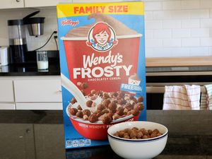 A box of Wendy's Frosty Cereal (and a bowl of the cereal) atop a black counter.