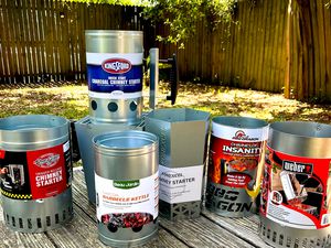 a variety of charcoal chimneys on a wooden picnic table