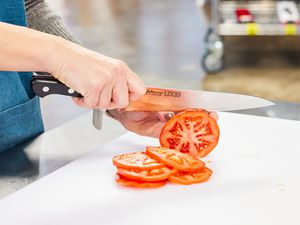 Hands slicing a tomato with a Misono UX10 8.2-Inch Gyutou