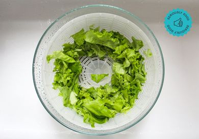 A glass salad spinner with salad greens in it