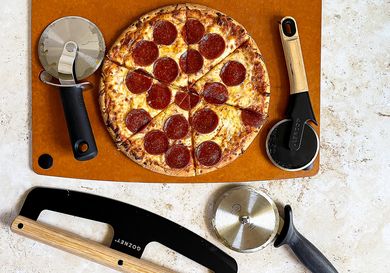 Pepperoni pizza on a board surrounded by pizza cutters